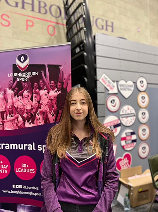 Student standing in front of sport signs